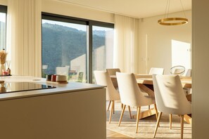 A modern dining area with a large table and chairs, a view of the outdoors, and a minimalist design. - Gerês Paradise (Vieira do Minho)