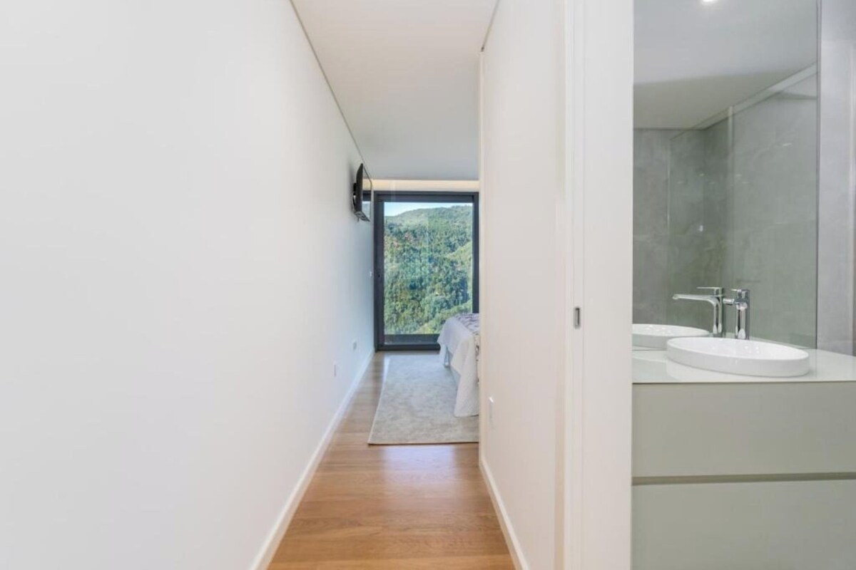 A modern bathroom with a large mirror, a sink, and a shower.