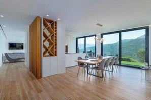 A modern kitchen with a dining area, large windows, and a view of the hills. - Gerês Paradise (Vieira do Minho)