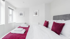 A hotel room with a large bed, white bedding, a grey headboard, and two framed pictures on the wall. - Walpole Court (London)