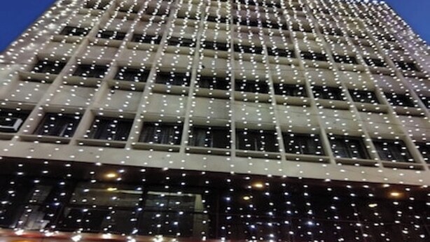 A hotel with a grid of windows and a sign reading "HOTEL RAINBOW BOARDING & LODGING". - Hotel Rainbow (Bengaluru)