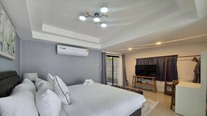 Ein Hotelzimmer mit einem großen Bett, einem Fernseher, einem Schreibtisch und einer Klimaanlage.