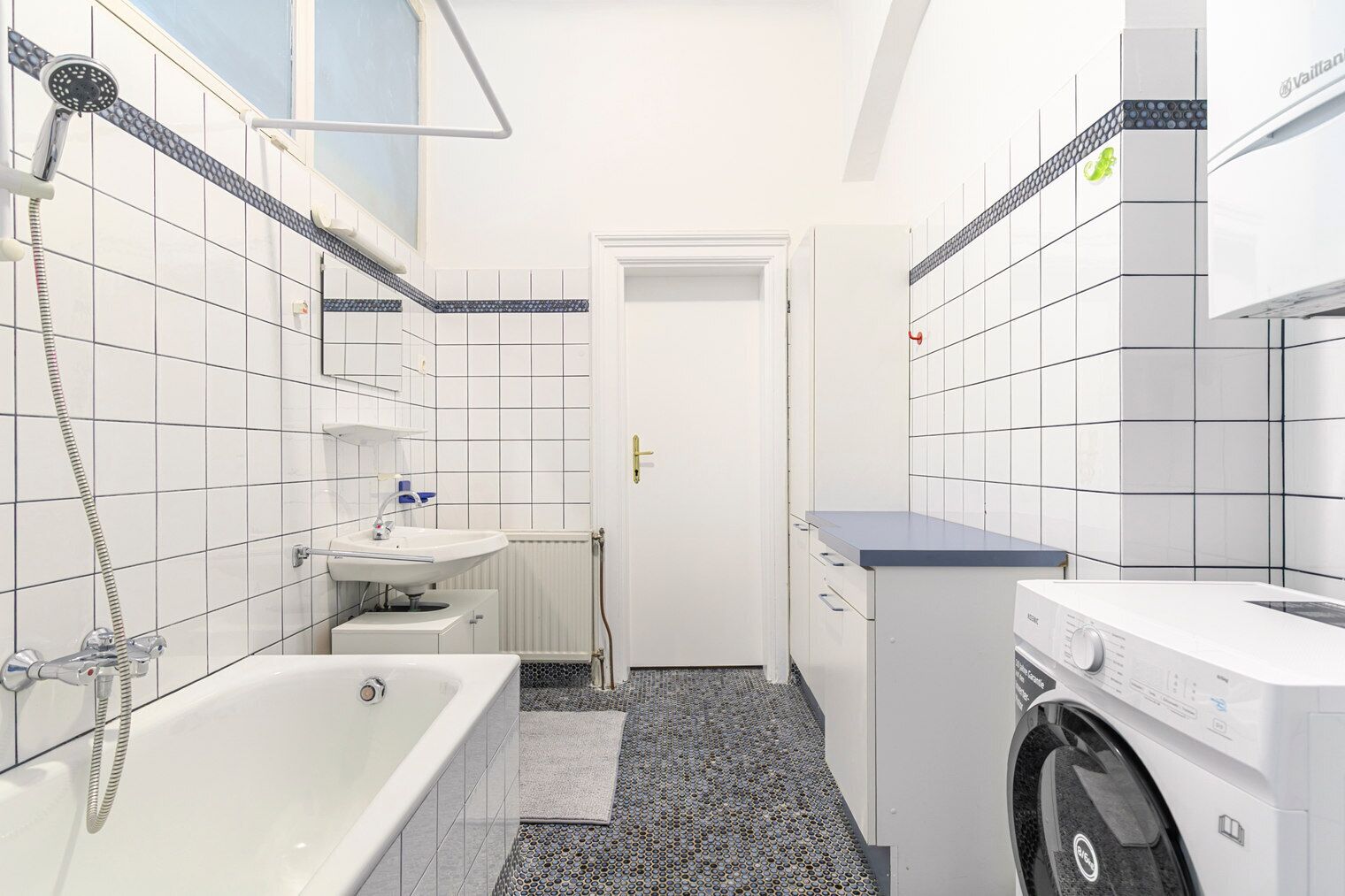 A compact bathroom with a bathtub, a sink, and a washing machine.