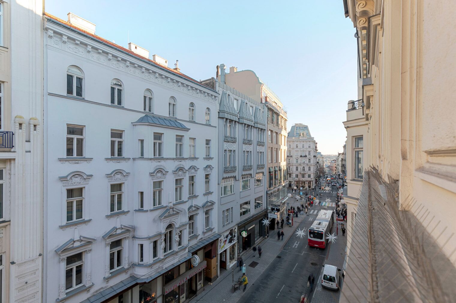 Vista de una calle en una ciudad con edificios históricos, un tranvía y peatones.
