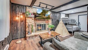 Une pièce chaleureuse avec une cheminée en pierre, une tente et un lit superposé.
