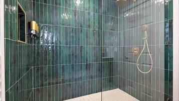 A glass-enclosed shower with a hexagonal floor tile design and a handheld showerhead.