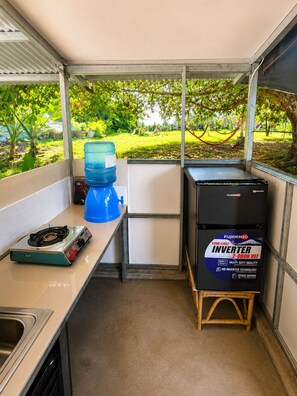 A compact kitchen with a gas stove, a water dispenser, and a Fujidenzo inverter. - Thrill Playgrounds & Tipi Cafe (Libona)
