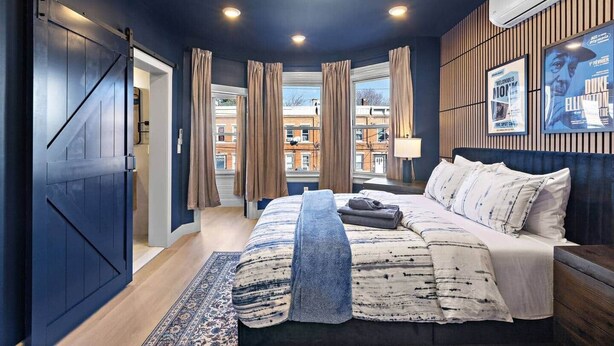 Een moderne slaapkamer met een groot bed, uitzicht op de stad en een plafondventilator.