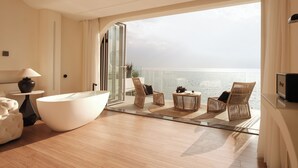 A modern hotel room with a large bathtub, wicker chairs, a round table, and a view of the sea. - Three types of cloud river snow shops (Dali)