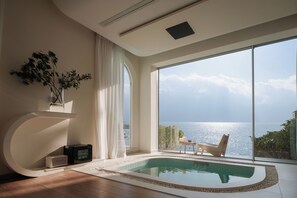 Ein modernes Zimmer mit großem Fenster, einer integrierten Whirlwanne und Meerblick.