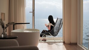 A room with a large window, a bathtub, and a chair facing the sea. - Three types of cloud river snow shops (Dali)