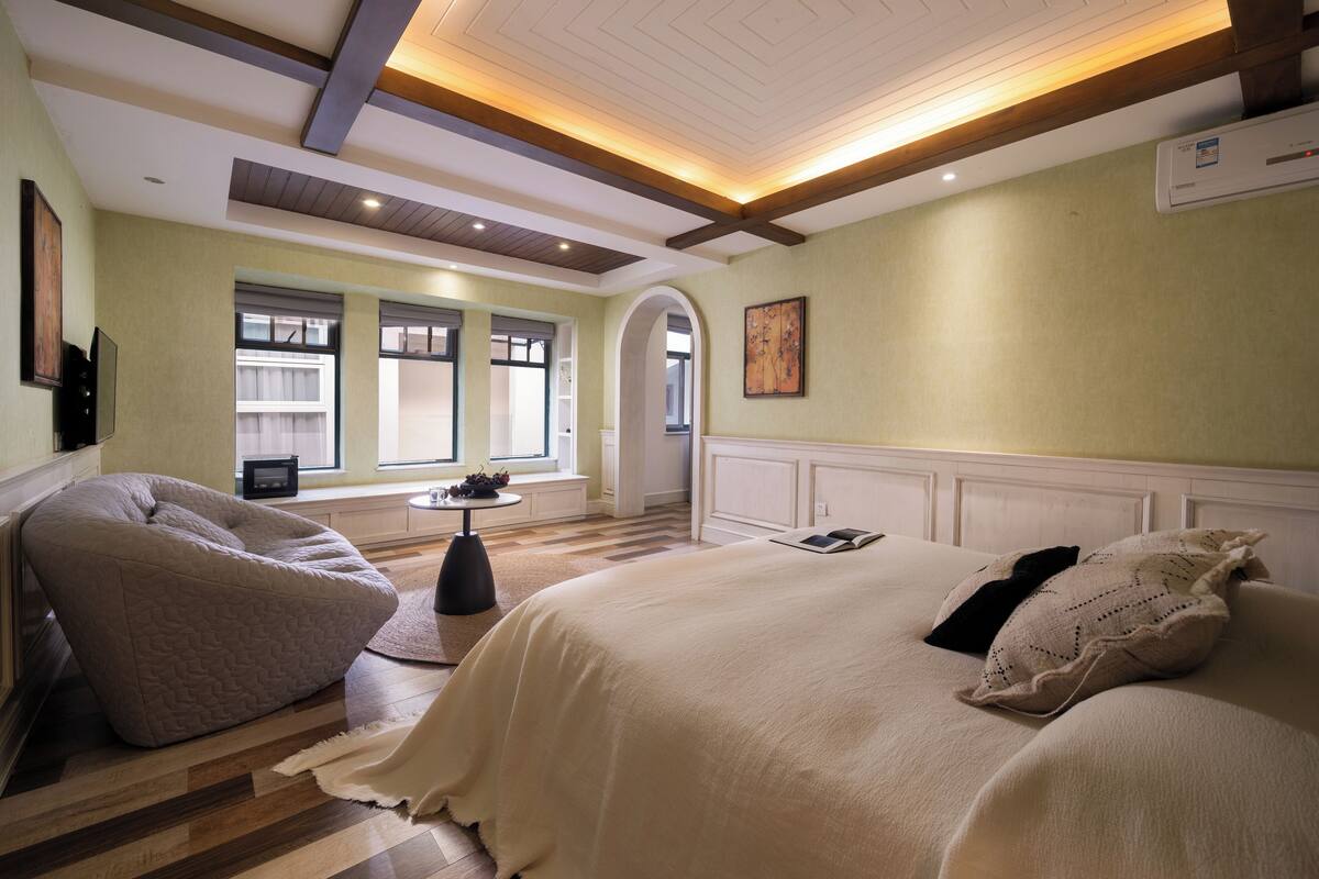 Un dormitorio con una cama grande, una mesita pequeña y una ventana con persianas.