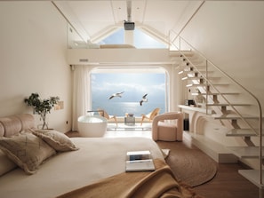 Ein modernes Schlafzimmer mit großem Fenster, einem Bett, einer Sitzecke und einer Treppe.