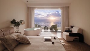 A modern bedroom with a large bathtub, a bed, a sofa, and a view of the sea. - Three types of cloud river snow shops (Dali)