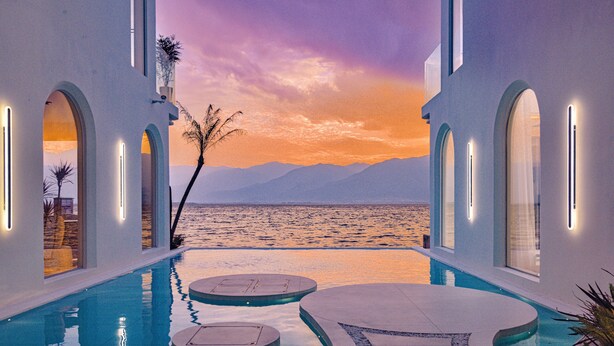 A pool area with a view of the sea and mountains, surrounded by white walls and arched doorways. - Three types of cloud river snow shops (Dali)