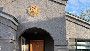 En bygning med en struktureret facade, en trædør og et cirkulært emblem over indgangen.