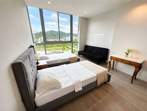 Un dormitorio moderno con un ventanal grande, una cama, un sofá y un escritorio.