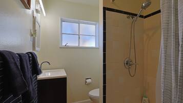A bathroom with a shower, toilet, and sink.