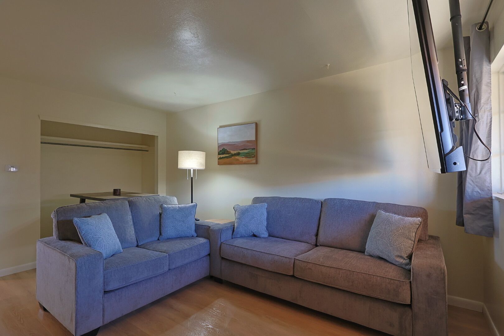 A living room with two sofas, a table, a lamp, and a painting on the wall.
