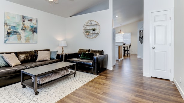 A modern living room with a leather sofa, coffee table, and a ceiling fan. - Meridian Gem / 1 King+ 2 Queens / Central location (Meridian)