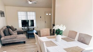 Una sala de estar con sofá, televisión y una mesa de comedor con sillas.