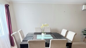 Een eethoek met een tafel, stoelen en een potorkidee.
