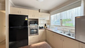 Een moderne keuken met een zwarte koelkast, een magnetron, een oven en een spoelbak.