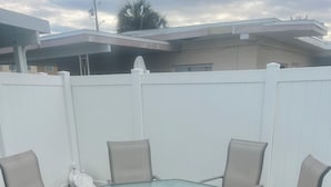 A glass-top outdoor table with six chairs, surrounded by a white fence. - 2 bedroom unit 2 blocks to the beautiful gulf beaches (Treasure Island)