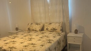 A bedroom with a bed, a nightstand, a lamp, a ceiling fan, and a window with curtains. - 2 bedroom unit 2 blocks to the beautiful gulf beaches (Treasure Island)