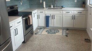 A modern kitchen with white cabinets, a stainless steel refrigerator, a microwave, and an oven. - 2 bedroom unit 2 blocks to the beautiful gulf beaches (Treasure Island)