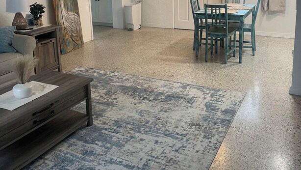 A living room with a coffee table, a painting, and a dining area with chairs and a table. - 2 bedroom unit 2 blocks to the beautiful gulf beaches (Treasure Island)