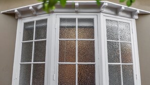 Een erker met witte sierlijsten en glaspanelen met structuur.