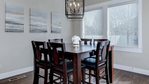 Une salle à manger avec une table et des chaises en bois, un lustre et des œuvres d’art accrochées aux murs.
