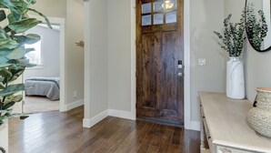 Un couloir avec une porte en bois, une plante et un vase posé sur une table.