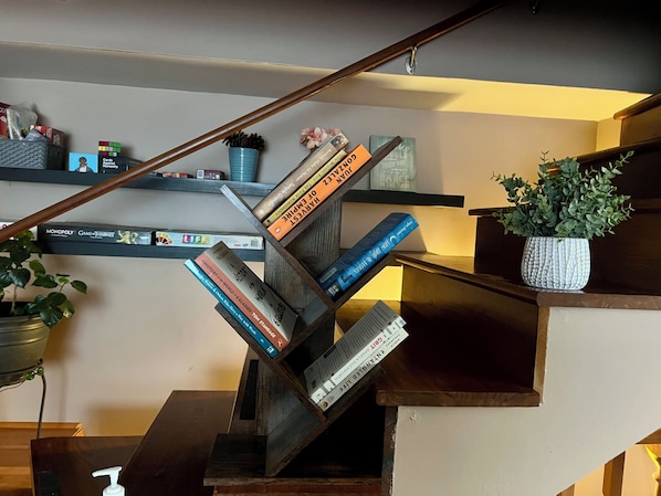 Een trap met boekenplanken aan weerszijden, een bloempot en een houten leuning.