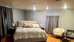 Una camera da letto moderna con un letto grande, lampade sui comodini, una poltrona e un tavolino.