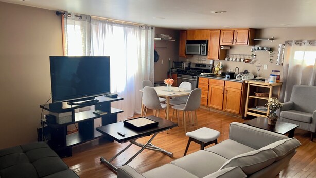 Un soggiorno con divano, televisore e zona pranzo con sedie e tavolo.