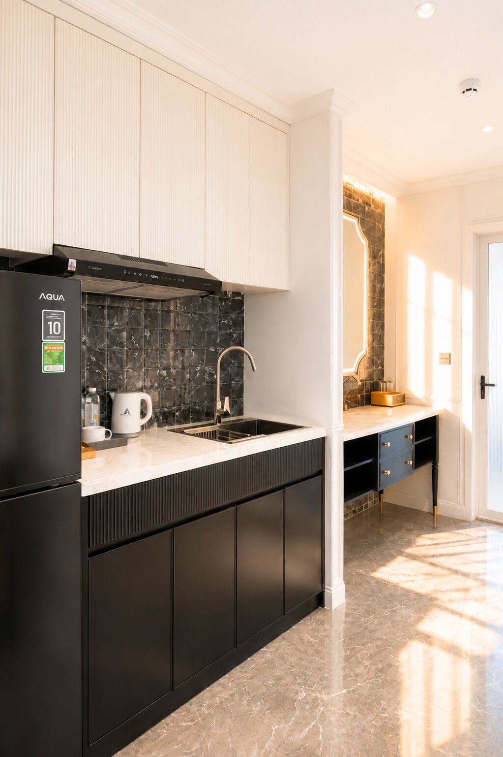 A modern kitchen with a black refrigerator, a marble countertop, and a black backsplash.
