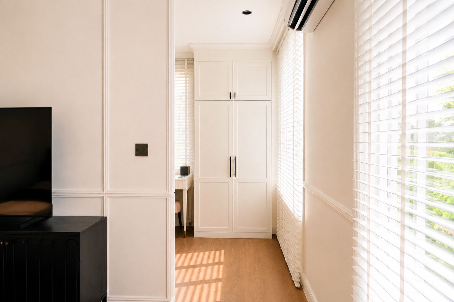 A hallway with a television, white cabinets, and a radiator.