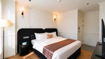 Una habitación de hotel con una cama grande, mesitas de noche, una lámpara y un televisor.