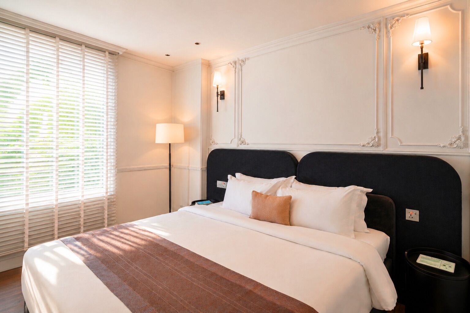 A hotel room with a bed, bedside lamp, and a nightstand.