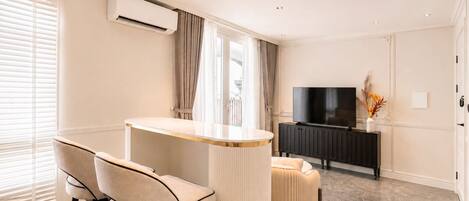 A modern living room with a bar area, a flat-screen TV, and a radiator.