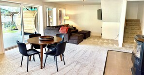 A living room with a sofa, ottoman, and a dining area with chairs and a table. - Cain Lakehouse with Outdoor Sauna (Sedro-Woolley)