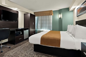 A hotel room with a large bed, a desk with a flat-screen TV, a microwave, and a small refrigerator.