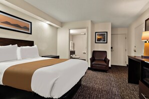 A hotel room with a bed, a desk, a chair, a bathroom, and a painting on the wall. - The Point Hotel (Memphis)