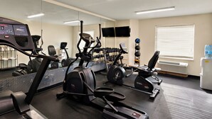 A gym with exercise equipment, a mirrored wall, and a water cooler. - The Point Hotel (Memphis)