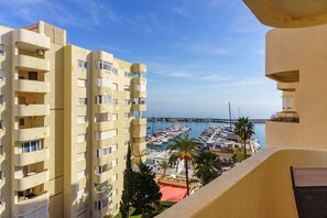 A high-rise building with multiple balconies overlooking a marina with boats and a pier. - Mirador del Puerto by Lica Homes (Estepona)