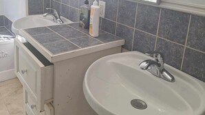 Ein Badezimmer mit zwei Waschbecken, einem Spiegel und einem Fenster mit Vorhängen.