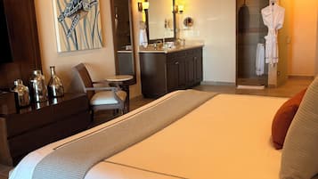 Hotellihuone, jossa on suuri sänky, työpöytä, peilillä varustettu meikkipöytä ja suihkutila.