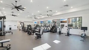 A modern gym with ceiling fans, various exercise equipment, and large windows. - Brand-New Build-Luxury 2BR Retreat-Resort Pool -Travel Nurse Friendly-Buckeye AZ (Buckeye)